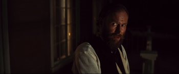Movie still from “The Magnificent Seven” (2016), directed by Antoine Fuqua – A man with a long beard wearing a vest and a tie; Close Up shot, Over the shoulder angle