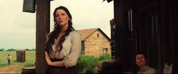 Movie still from “The Magnificent Seven” (2016), directed by Antoine Fuqua – A woman standing in front of a wooden house; Medium shot, Low angle