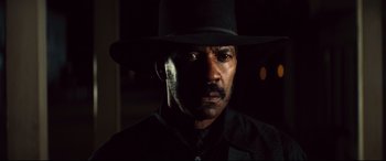 Movie still from “The Magnificent Seven” (2016), directed by Antoine Fuqua – A man in a black hat is looking at the camera; Close Up shot, Over the shoulder angle