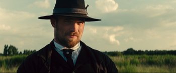 Movie still from “The Magnificent Seven” (2016), directed by Antoine Fuqua – A person wearing a hat and a suit; Close Up shot, Over the shoulder angle