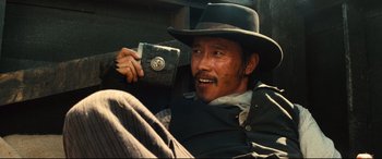 Movie still from “The Magnificent Seven” (2016), directed by Antoine Fuqua – A man in a cowboy hat holding a wallet; Close Up shot, Low angle