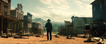 Movie still from “The Magnificent Seven” (2016), directed by Antoine Fuqua – A man in a cowboy hat standing in the middle of an empty street; Wide shot, Low angle
