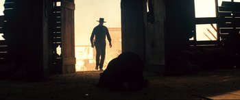 Movie still from “The Magnificent Seven” (2016), directed by Antoine Fuqua – A man in a cowboy hat walking down a street; Wide shot, Low angle