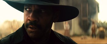 Movie still from “The Magnificent Seven” (2016), directed by Antoine Fuqua – A person wearing a hat; Close Up shot, Over the shoulder angle