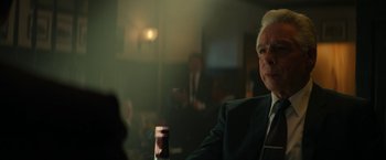 Movie still from “The Offer” (2022), directed by Dexter Fletcher – A man in a suit sitting at a table; Close Up shot, Over the shoulder angle