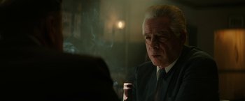 Movie still from “The Offer” (2022), directed by Dexter Fletcher – An older man smoking a cigarette in a dimly - lit room; Close Up shot, Over the shoulder angle