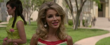 Movie still from “The Offer” (2022), directed by Dexter Fletcher – A woman with blonde hair wearing a red , white , and green dress; Close Up shot, Over the shoulder angle
