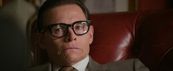 Movie still from “The Offer” (2022), directed by Dexter Fletcher – A person wearing a suit and glasses; Close Up shot, Over the shoulder angle