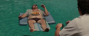 Movie still from “The Offer” (2022), directed by Dexter Fletcher – A man is laying in the water with a bowl of pasta; Medium shot, Overhead angle