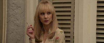 Movie still from “The Offer” (2022), directed by Dexter Fletcher – A woman with blonde hair is holding a cigarette in her mouth; Close Up shot, Over the shoulder angle