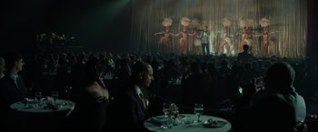 Movie still from “The Offer” (2022), directed by Dexter Fletcher – A man sitting at a table in front of an audience; Extreme Wide shot, High angle