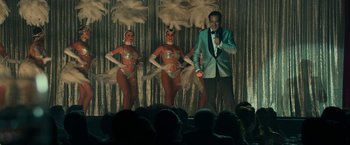 Movie still from “The Offer” (2022), directed by Dexter Fletcher – A man standing in front of two showgirls on a stage; Medium shot, Over the shoulder angle