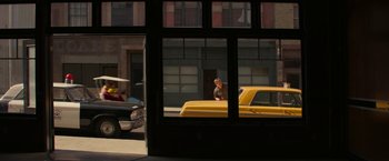 Movie still from “The Offer” (2022), directed by Dexter Fletcher – A man standing next to a yellow truck on the side of the road; Wide shot, Over the shoulder angle