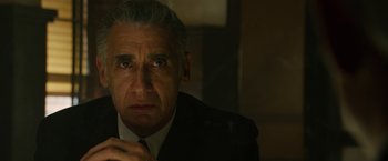 Movie still from “The Offer” (2022), directed by Dexter Fletcher – An older man wearing a suit and tie looking at the camera; Close Up shot, Low angle