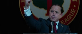 Movie still from “The Offer” (2022), directed by Dexter Fletcher – A man in a suit and tie raising his fist; Close Up shot, Low angle