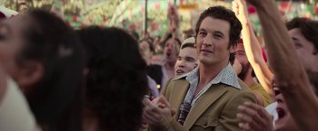 Movie still from “The Offer” (2022), directed by Dexter Fletcher – A man clapping at an outdoor event while others watch; Close Up shot, Over the shoulder angle