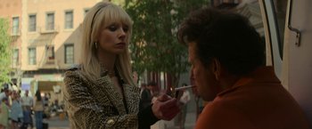 Movie still from “The Offer” (2022), directed by Dexter Fletcher – A woman lighting a cigarette in front of a man on the street; Close Up shot, Over the shoulder angle