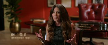 Movie still from “The Offer” (2022), directed by Dexter Fletcher – A woman with long brown hair is sitting in a room; Medium shot, High angle