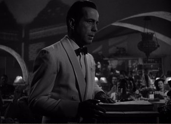Movie still from “Casablanca” (1942), directed by Michael Curtiz – A black and white photo of a man in a suit and bow tie; Medium shot, Over the shoulder angle