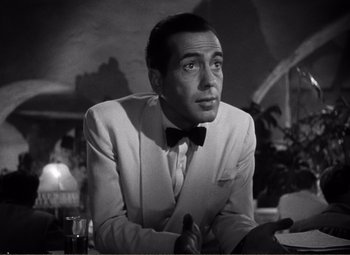 Movie still from “Casablanca” (1942), directed by Michael Curtiz – A black and white photo of a man in a white suit; Close Up shot, Low angle
