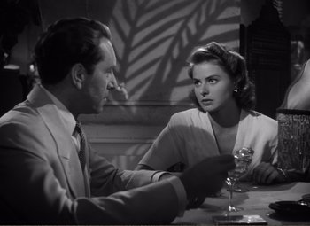 Movie still from “Casablanca” (1942), directed by Michael Curtiz – A man and a woman sitting at a dinner table; Medium shot, Over the shoulder angle