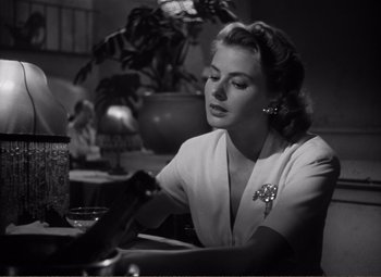 Movie still from “Casablanca” (1942), directed by Michael Curtiz – A black and white photo of a woman sitting at a table; Close Up shot, Low angle