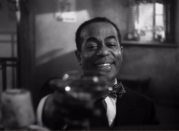 Movie still from “Casablanca” (1942), directed by Michael Curtiz – A man in a suit and bow tie holding a glass of wine; Close Up shot, Low angle