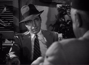 Movie still from “Casablanca” (1942), directed by Michael Curtiz – A man wearing a suit and tie and a hat; Close Up shot, Over the shoulder angle