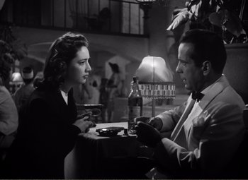 Movie still from “Casablanca” (1942), directed by Michael Curtiz – A man and a woman sitting at a table in front of a lamp; Medium shot, Low angle