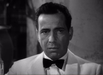 Movie still from “Casablanca” (1942), directed by Michael Curtiz – Black and white photograph of a man wearing a suit and bow tie; Close Up shot, Low angle