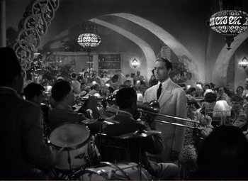 Movie still from “Casablanca” (1942), directed by Michael Curtiz – A man standing in front of a group of people in a room; Wide shot, High angle
