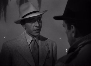 Movie still from “Casablanca” (1942), directed by Michael Curtiz – A man wearing a suit and a hat talking to another man wearing a hat; Close Up shot, Over the shoulder angle