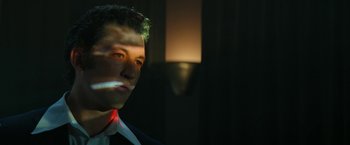 Movie still from “The Offer” (2022), directed by Dexter Fletcher – A man in a suit and tie in a dark room; Close Up shot, Low angle