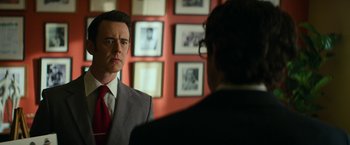 Movie still from “The Offer” (2022), directed by Dexter Fletcher – A man wearing a suit and tie looking at himself in the mirror; Close Up shot, Over the shoulder angle