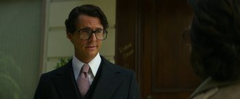 Movie still from “The Offer” (2022), directed by Dexter Fletcher – A man in a suit and tie wearing glasses; Close Up shot, Low angle