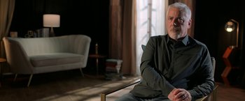 Movie still from “The Offer” (2022), directed by Dexter Fletcher – An older man sitting on a chair in a living room; Medium shot, Over the shoulder angle