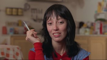 Movie still from “The Shining” (1980), directed by Stanley Kubrick – A woman holding a pen in her right hand; Close Up shot, Low angle