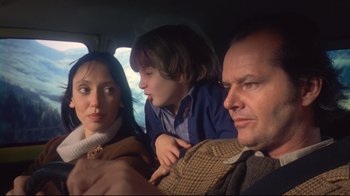 Movie still from “The Shining” (1980), directed by Stanley Kubrick – A man and a woman and a child in a car; Medium shot, High angle