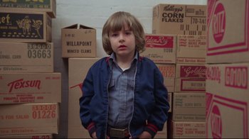 Movie still from “The Shining” (1980), directed by Stanley Kubrick – A young boy standing in front of a wall filled with boxes; Medium shot, Low angle