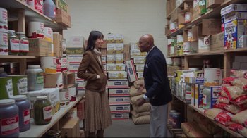 Movie still from “The Shining” (1980), directed by Stanley Kubrick – A man and a woman standing in front of boxes of food; Wide shot, Over the shoulder angle