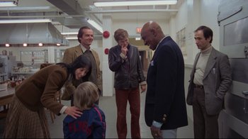 Movie still from “The Shining” (1980), directed by Stanley Kubrick – A group of people standing in a hallway; Wide shot, Over the shoulder angle