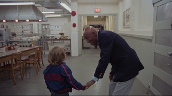 Movie still from “The Shining” (1980), directed by Stanley Kubrick – An older man and a young boy shaking hands in a room; Medium shot, Over the shoulder angle