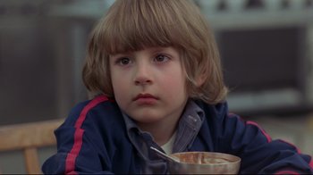 Movie still from “The Shining” (1980), directed by Stanley Kubrick – A young boy is sitting in front of a bowl of cereal; Close Up shot, Over the shoulder angle