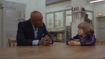 Movie still from “The Shining” (1980), directed by Stanley Kubrick – A man sitting at a table talking to a child; Medium shot, Over the shoulder angle