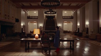 Movie still from “The Shining” (1980), directed by Stanley Kubrick – Two people sitting at a table in front of a staircase; Extreme Wide shot, Low angle
