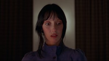 Movie still from “The Shining” (1980), directed by Stanley Kubrick – A woman with long black hair wearing a purple shirt; Close Up shot, Low angle