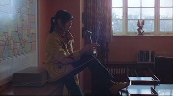 Movie still from “The Shining” (1980), directed by Stanley Kubrick – A woman sitting on top of a wooden bench in front of a window; Medium shot, Low angle