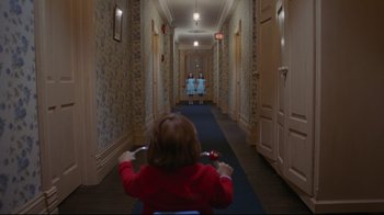 Movie still from “The Shining” (1980), directed by Stanley Kubrick – A little girl riding a bike down a hallway; Wide shot, Over the shoulder angle