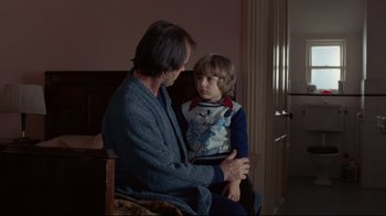 Movie still from “The Shining” (1980), directed by Stanley Kubrick – A man and a boy sitting in a room; Medium shot, Over the shoulder angle
