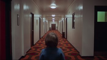 Movie still from “The Shining” (1980), directed by Stanley Kubrick – A person standing in a hallway of a hotel; Wide shot, High angle